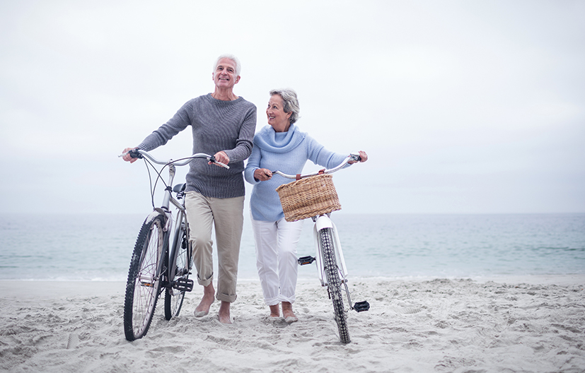 Older couple riding bikes in the sand