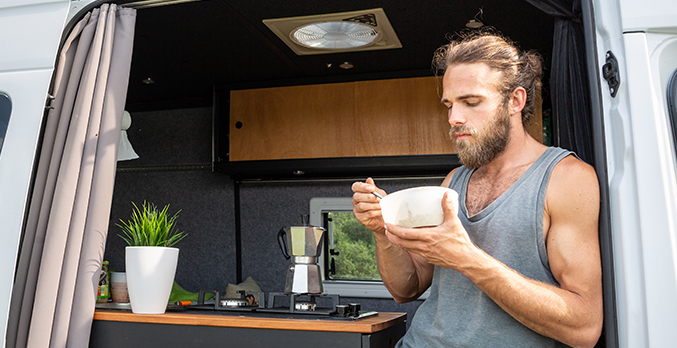 man eating breakfast inside of conversion van rv