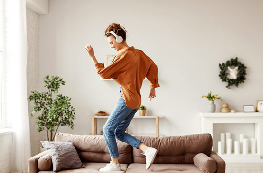 woman dancing in living room with headphones on