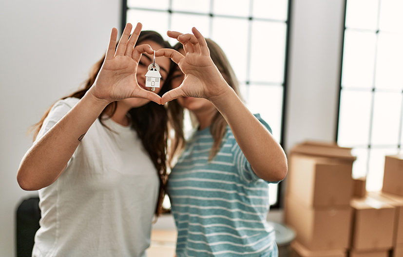 young couple holding keys to new home forming hands into a heart