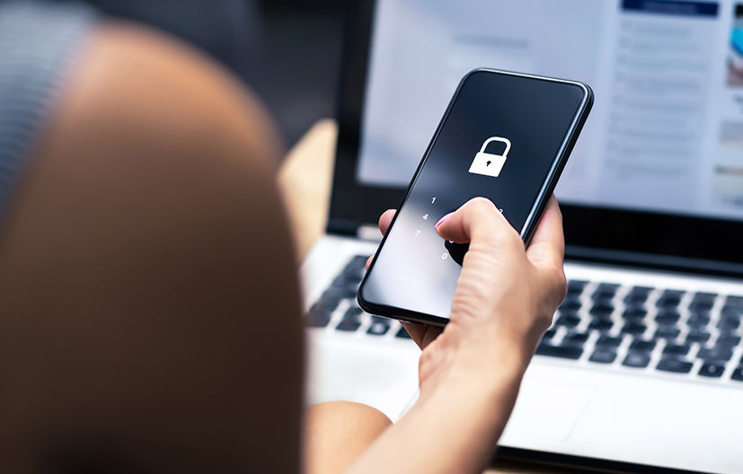 hand holding phone with pad lock in front of computer