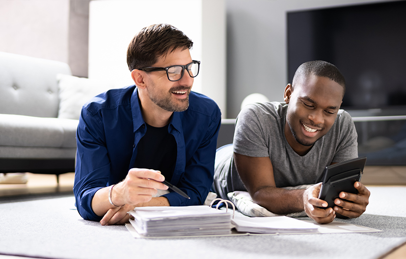 two men laying on the floor looking at smartphone
