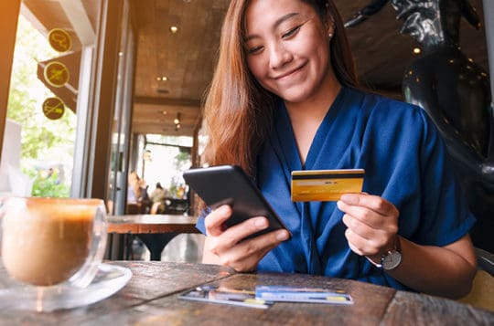 Closeup image of person using credit card for purchasing and shopping online on mobile phone